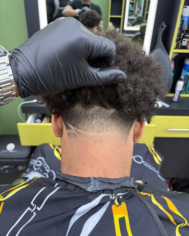 Barber cutting a curly taper fade at Edward Style Barbershop